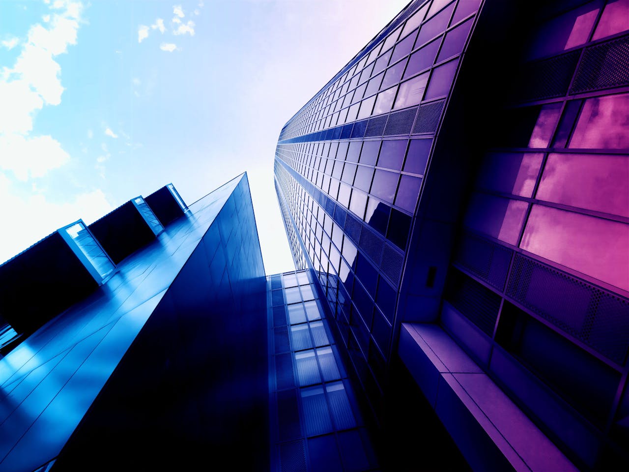 services-01 Low angle shot of modern skyscrapers with reflective glass facades and vibrant colors in an urban setting.